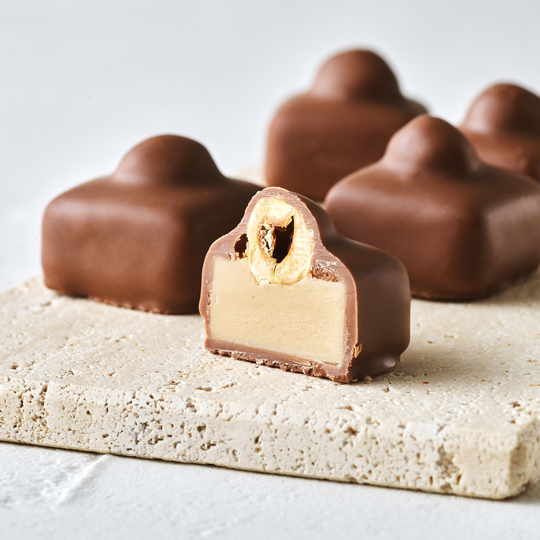 Stimmungsbild: Haselnuss-Nougat Praline mit Vollmilchschokolade überzogen dekorativ angeschnitten Stimmungsbild: Haselnuss-Nougat Praline mit Vollmilchschokolade überzogen dekorativ angeschnitten