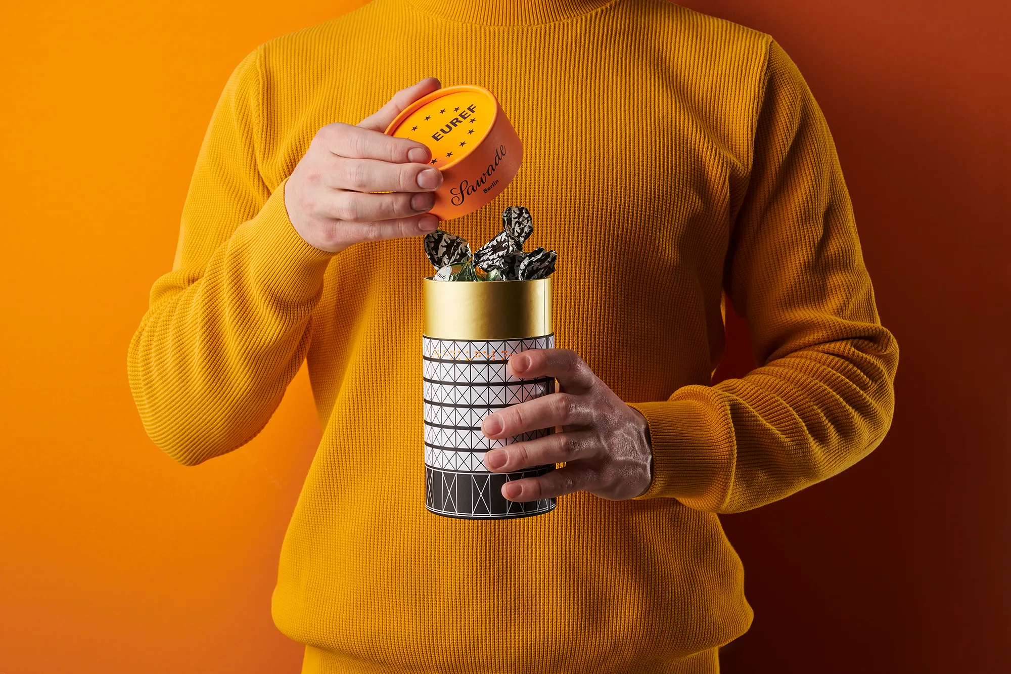 Mensch öffenet eine Geschenkdose mit Pralinenkugeln vom EUREF Campus