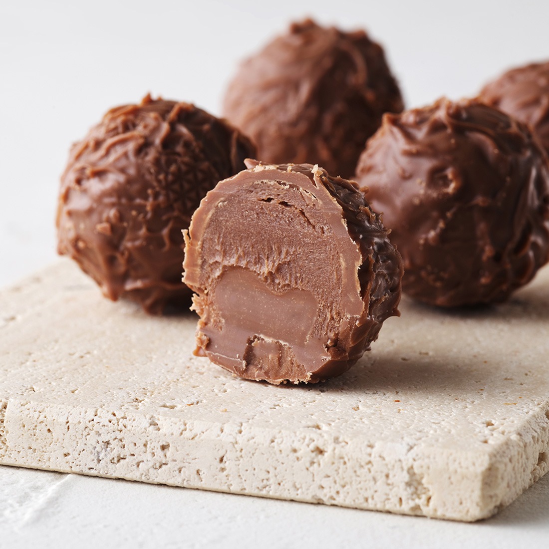 Stimmungsbild: Schokoladen-Butter Trüffel mit Vollmilchschokolade geigelt dekorativ angeschnitten Stimmungsbild: Schokoladen-Butter Trüffel mit Vollmilchschokolade geigelt dekorativ angeschnitten