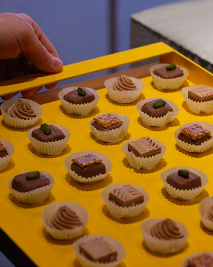 Stimmungsbild: verschiedene Pralinen auf einem strahlend gelben Tablett