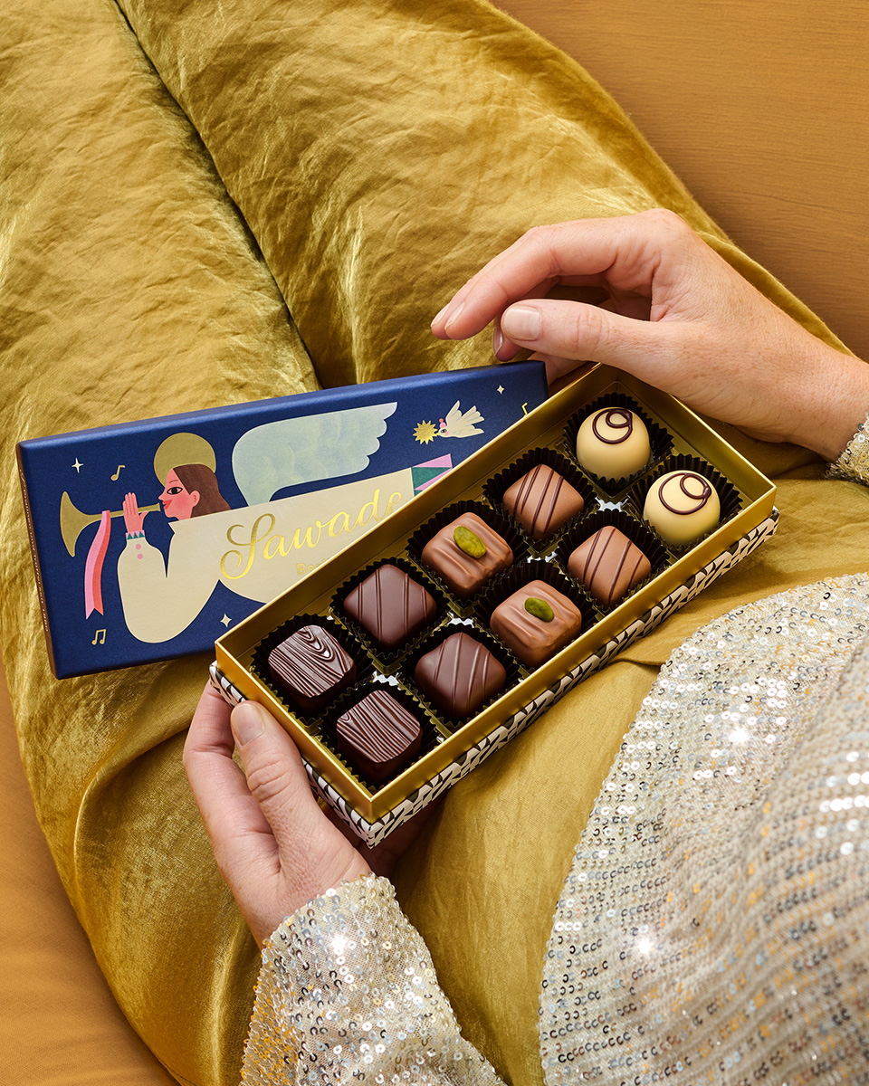 Pralinenschachtel Engel geöffnet auf dem Schoß einer jungen Frau