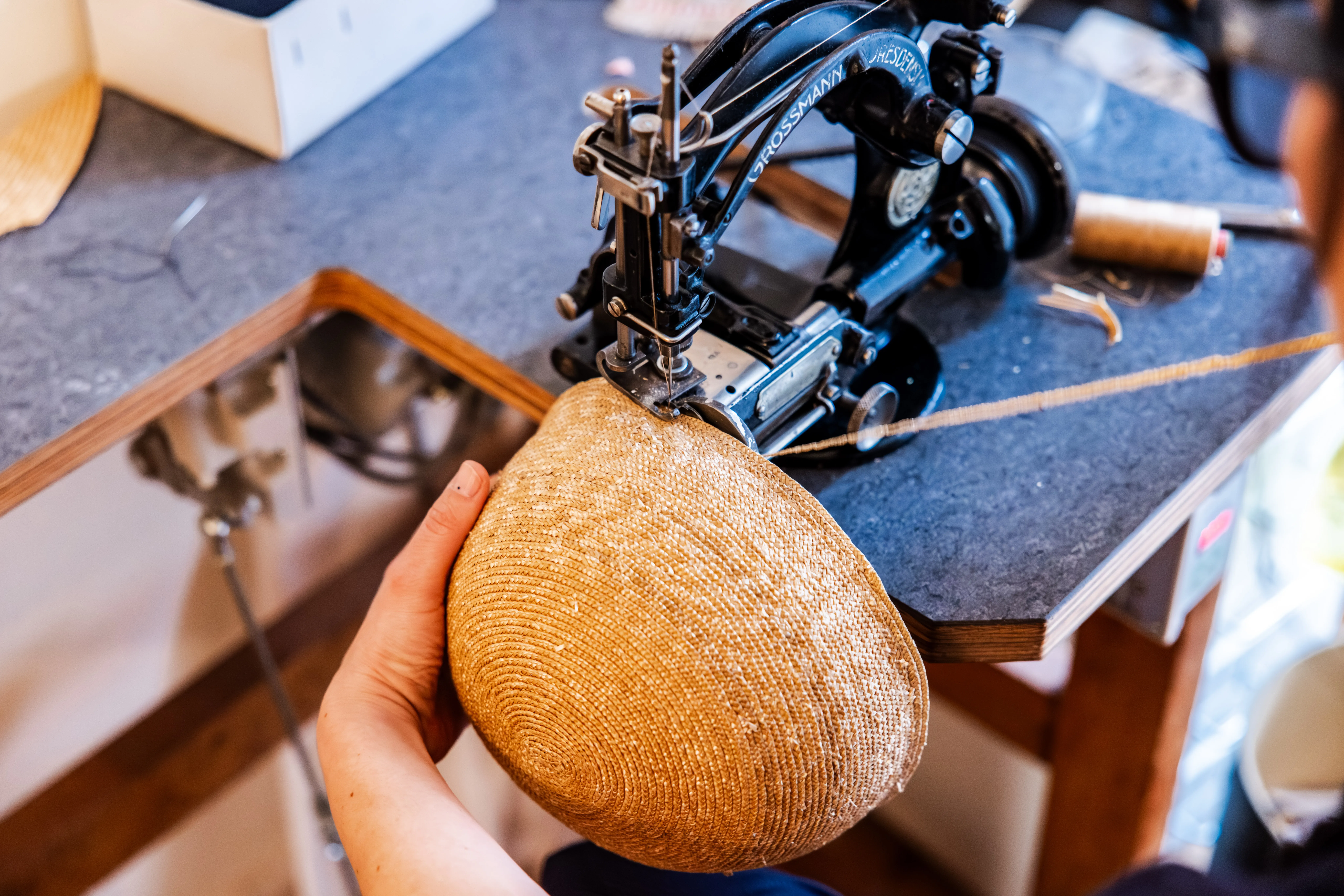 Nahaufnahme des Nähvorganges eines Strohhutes an der Nähmaschine.