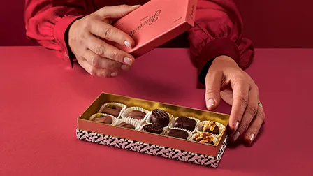 Stimmungsbild: Hand greift in violette Schachtel mit Pralinen