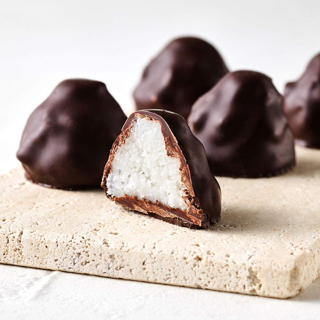 Stimmungsbild: Kokosflocke Praline mit Zartbitterschokolade dekorativ angeschnitten Stimmungsbild: Kokosflocke Praline mit Zartbitterschokolade dekorativ angeschnitten