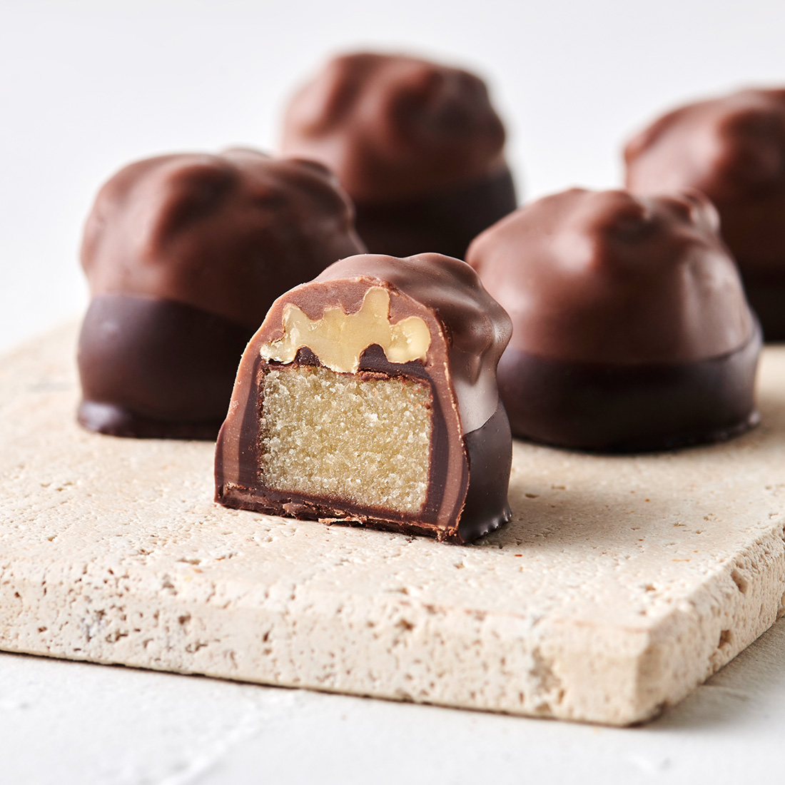 Stimmungsbild: Bordeauxnuss Praline in Zartbitterschokolade und Vollmilchschokolade getaucht dekorativ angeschnitten  Stimmungsbild: Bordeauxnuss Praline in Zartbitterschokolade und Vollmilchschokolade getaucht dekorativ angeschnitten
