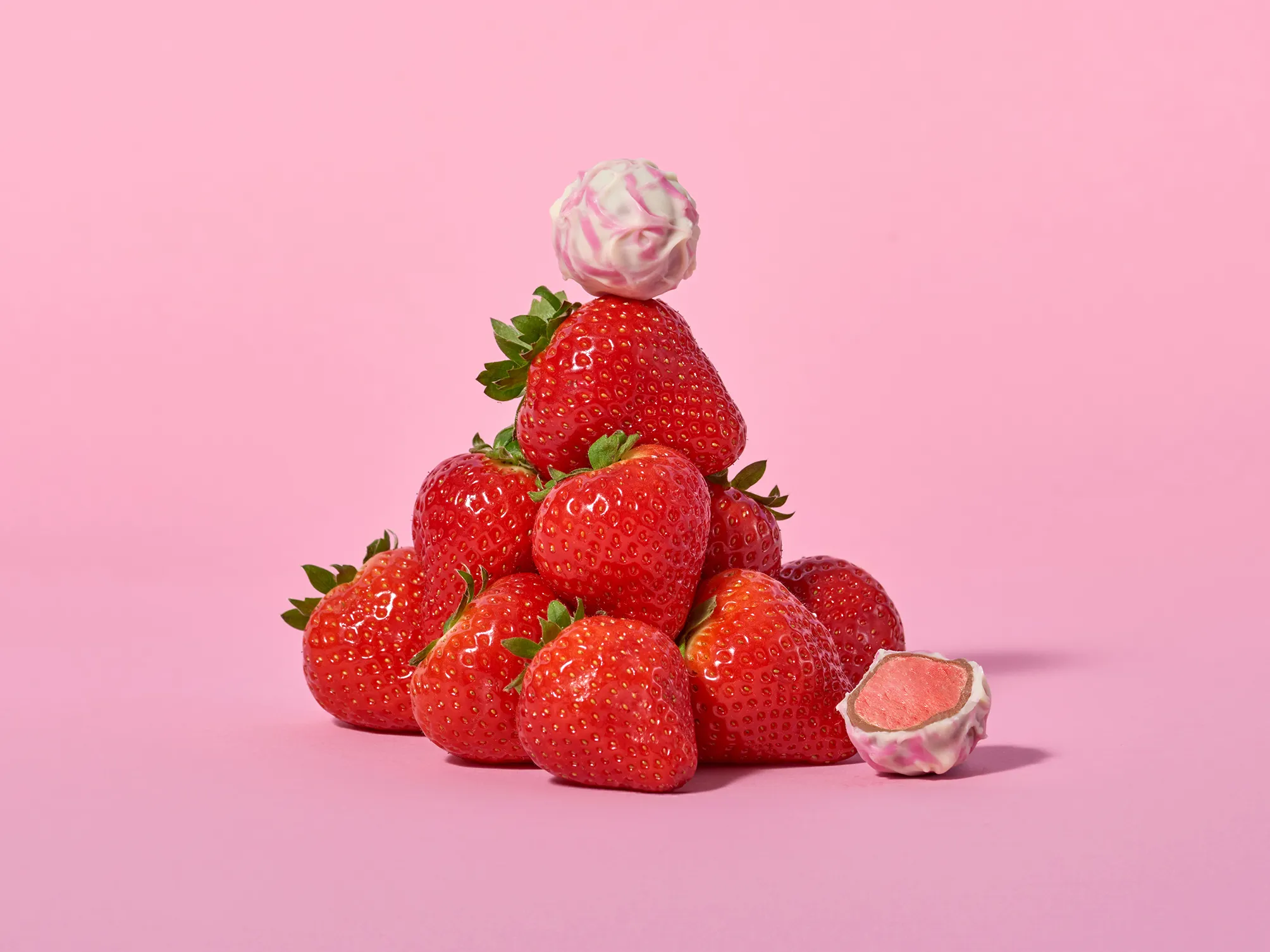 Stimmungsbild: Erdbeer-Joghurt dekorativ aufgeschnitten mit Erdbeeren und rosa Hintergrund 