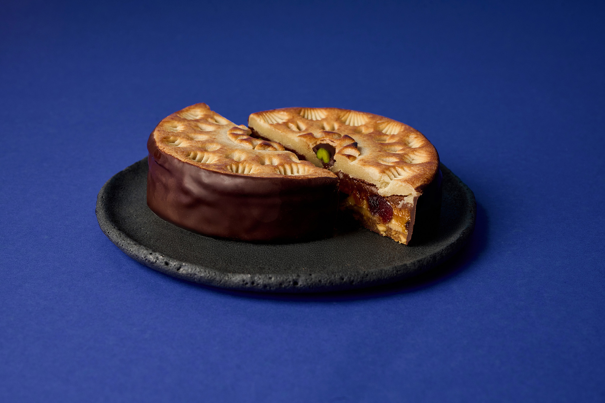 Stimmungsbild: Sawade Torte in der Hälfte geschnitten auf schwarzem Teller und blauem Hintergrund