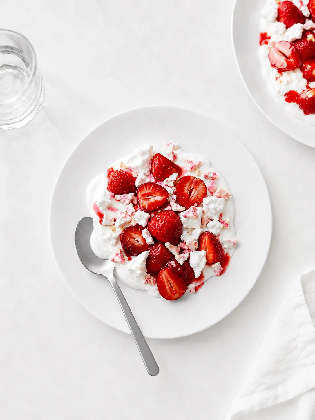 Stimmungsbild: Dessert mit Erdbeeren, Sahne und eisgekühlten Pralinen auf einem weißen Teller
