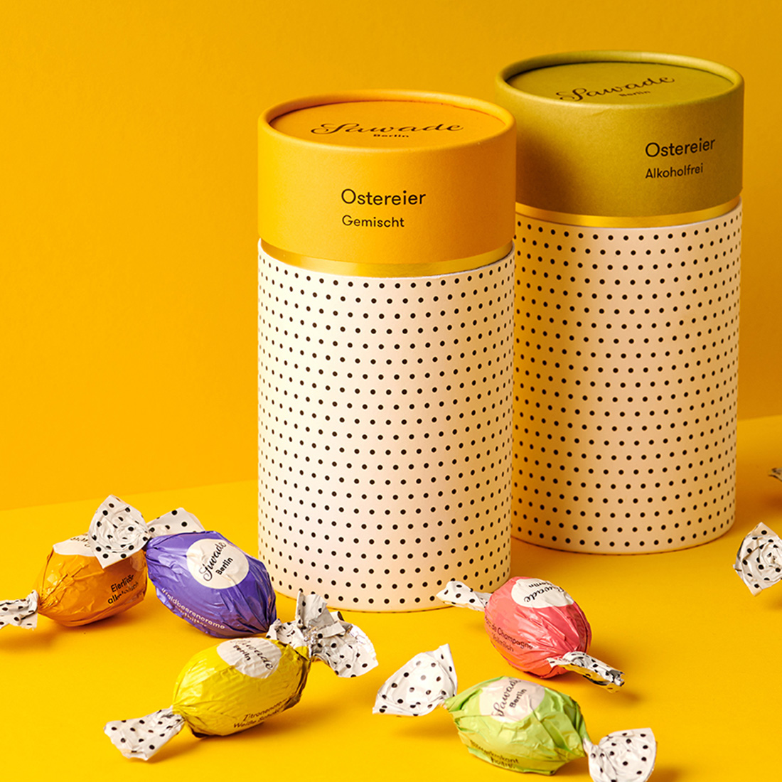 Stimmungsbild: Gemischte Ostereier und zwei Geschenkdosen stehen dekorativ mit gelben Untergrund Stimmungsbild: Gemischte Ostereier und zwei Geschenkdosen stehen dekorativ mit gelben Untergrund