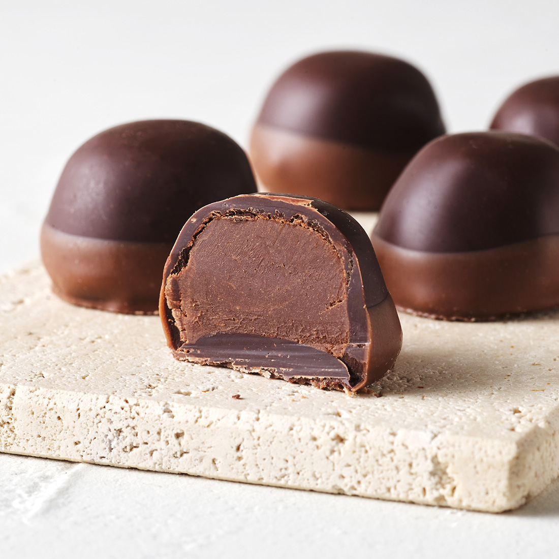 Stimmungsbid: Rum-Sahne-Trüffel mit Zartbitterschokolade in Vollmlichschokolade getaucht dekorativ aufgeschnitten Stimmungsbid: Rum-Sahne-Trüffel mit Zartbitterschokolade in Vollmlichschokolade getaucht dekorativ aufgeschnitten