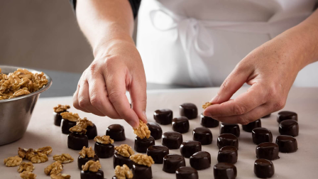 Eine Frau legt halbe Walnüsse auf Marzipan Pralinen Eine Frau legt halbe Walnüsse auf Marzipan Pralinen