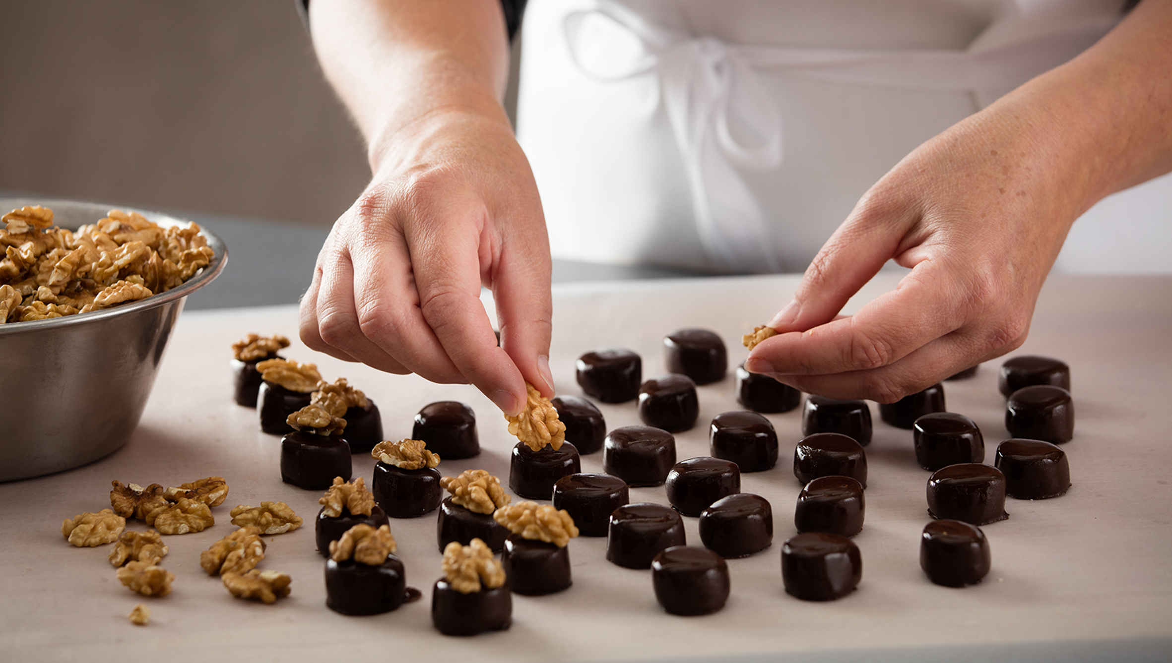 Stimmungsbild: Marzipan-Walnuss Pralinen werden in der Produktion mit Walnüssen belegt